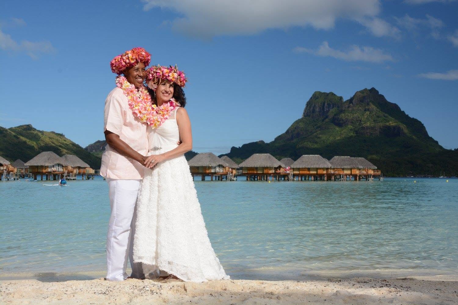 Jill and Lori on their wedding day in Bora Bora, wearing flower crowns on the beach