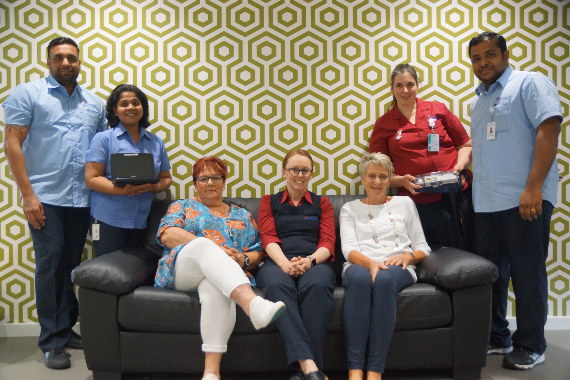 Working together ... (From left): Garry Singh, Kimi Joseph holding the donated music player, Lions Ladies president Pauline Stuart, Catherine Church and Bernadette Steward seated on the donated sofa-bed, Michelle Cleary holding the donated syringe driver, and Abyson Abraham. 