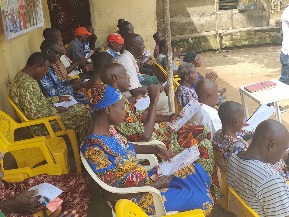 Image shows a community meeting of Nigerian cocoa farmers. 