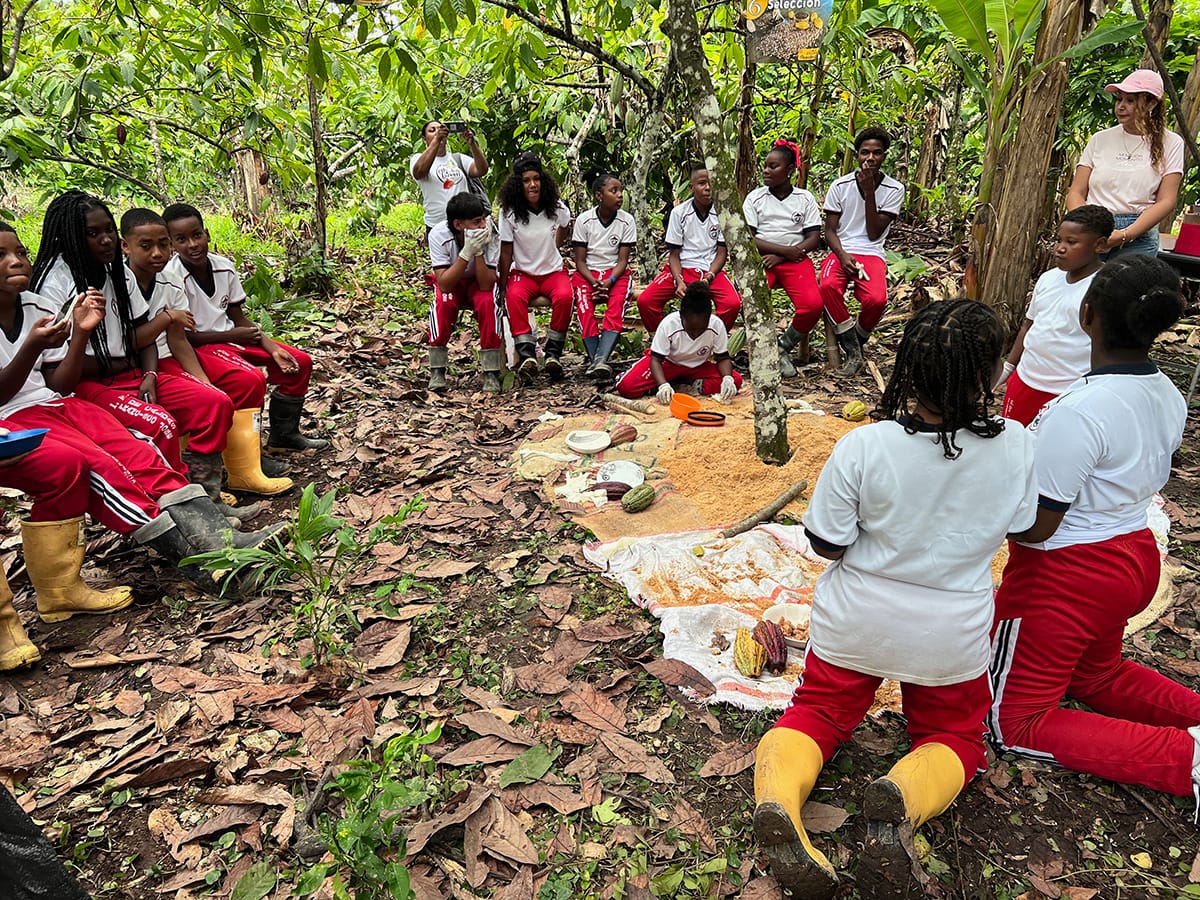 Image shows school children visiting a Luker cocoa farm.