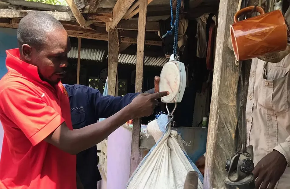 Images shows a buyer weighing cocoa beans at a collection point in Ghana.