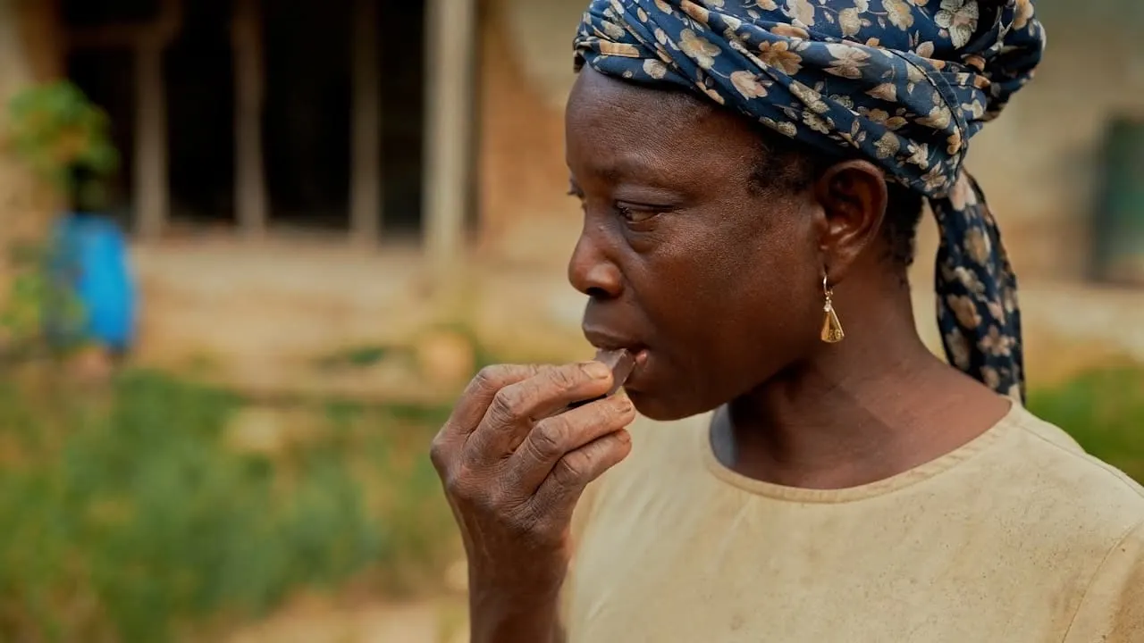 Image shows a Ghanaian woman eating a piece of chocolat