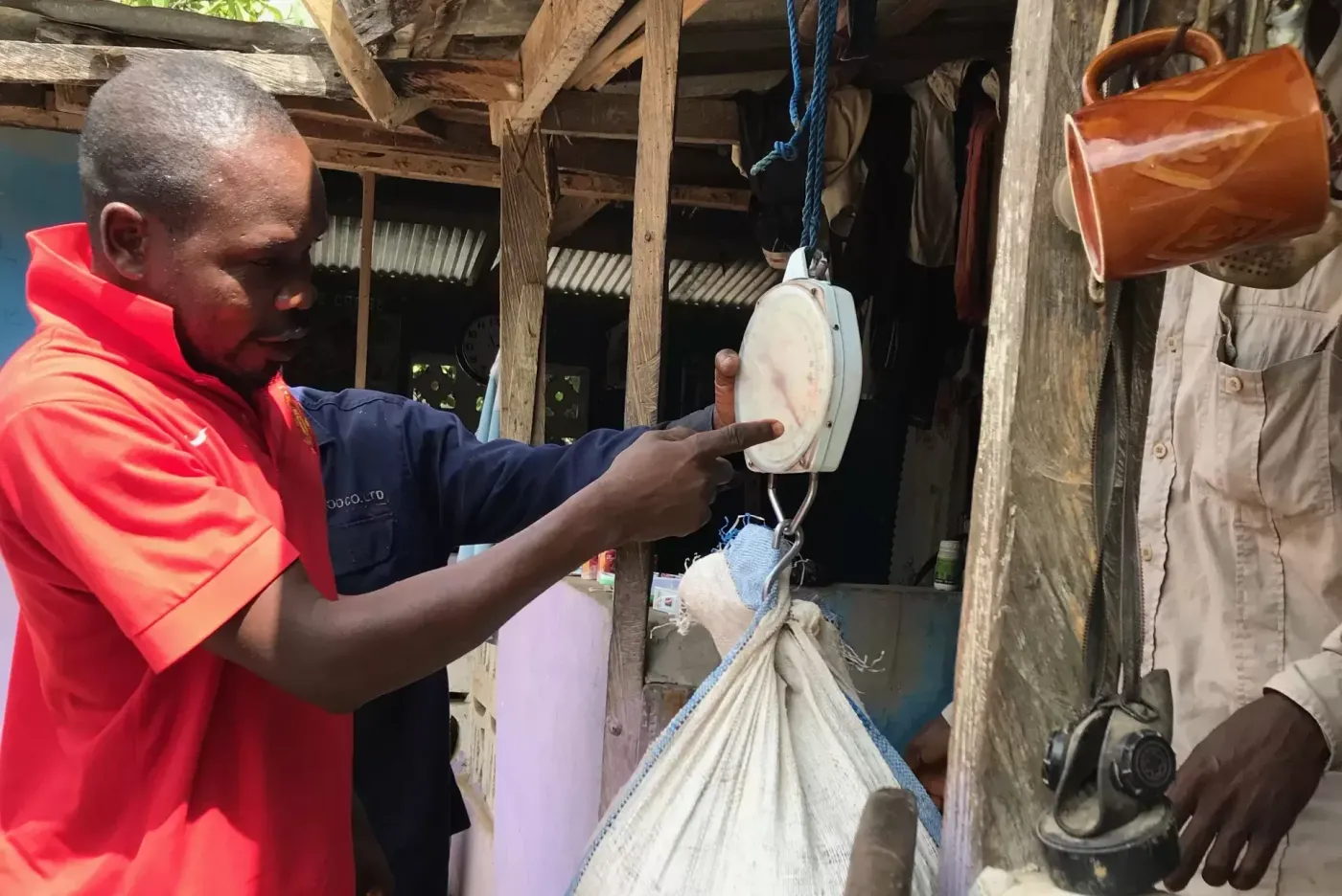Image shows a A purchasing clerk in Ghana weighing beans bought from a farmer. Image: African Cocoa Marketplace.