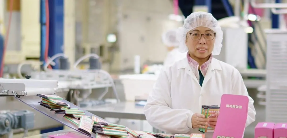 Image shows a US factory worker packing chocolate 