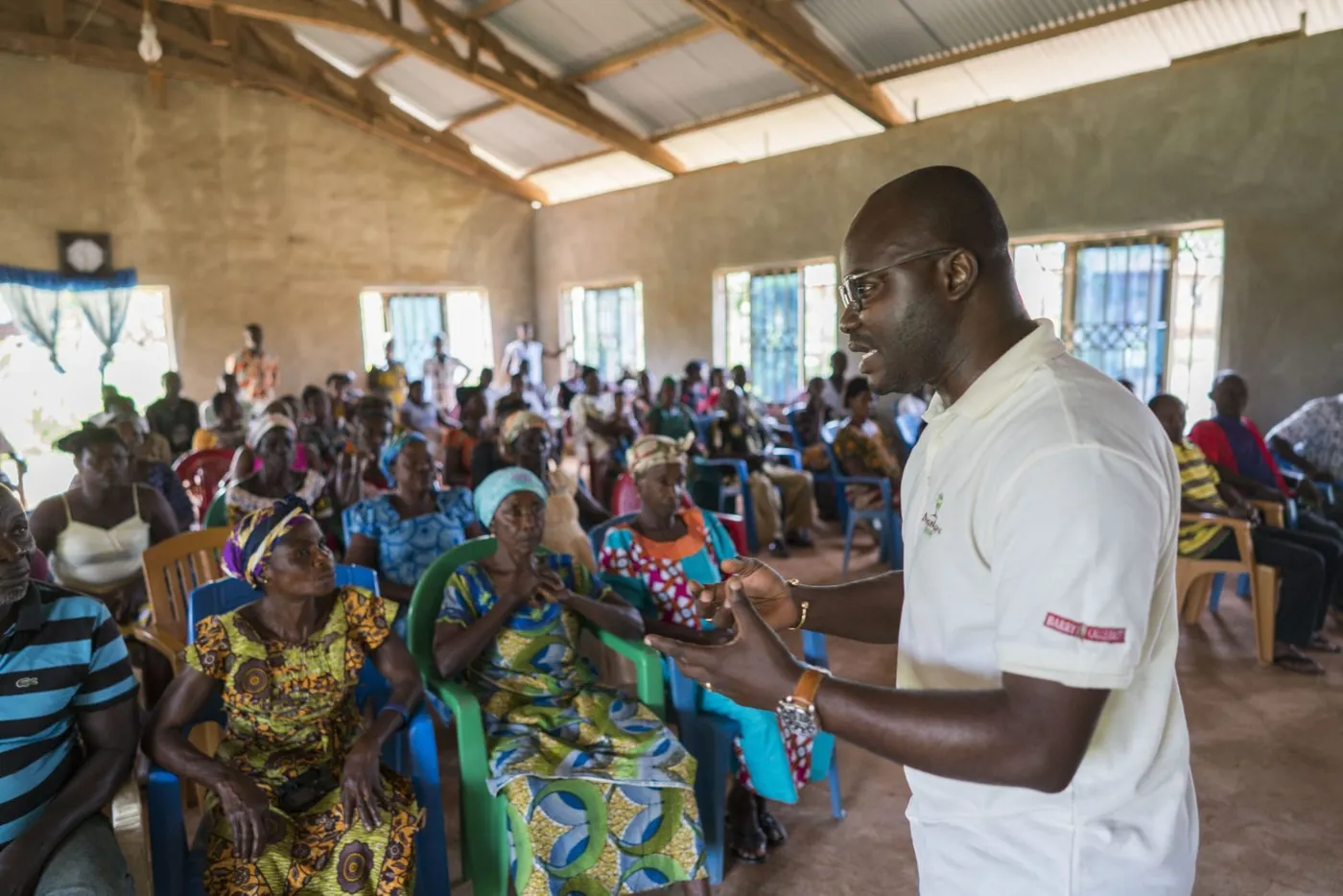 Image shows a female cocoa cooperative in Africa, listening to a Barry Callebaut trainers