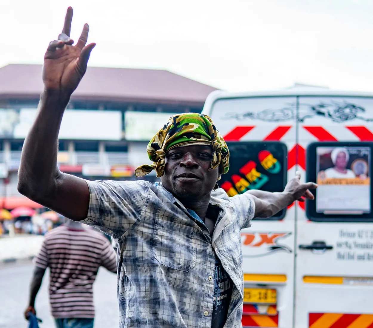 Image shows a street scene in Ghana with a man directing traffic.