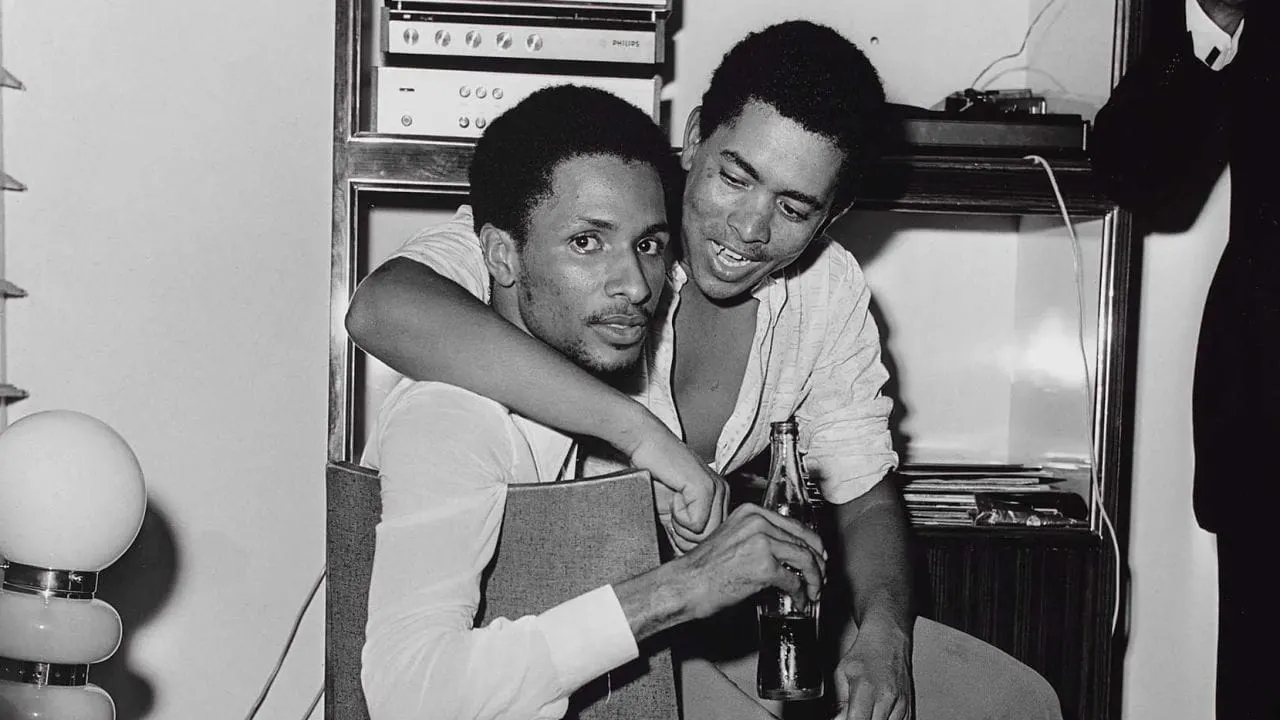 Image shows two men embracing from 1970s Ivorian photography by Paul Kodjo.