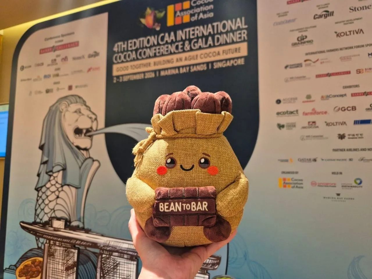 Image shows a novelty bean to bar bag held in front of the CAA Conference sponsor panel.