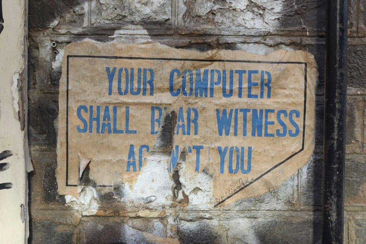A tattered sign that once read, "Your computer shall bear witness against you."