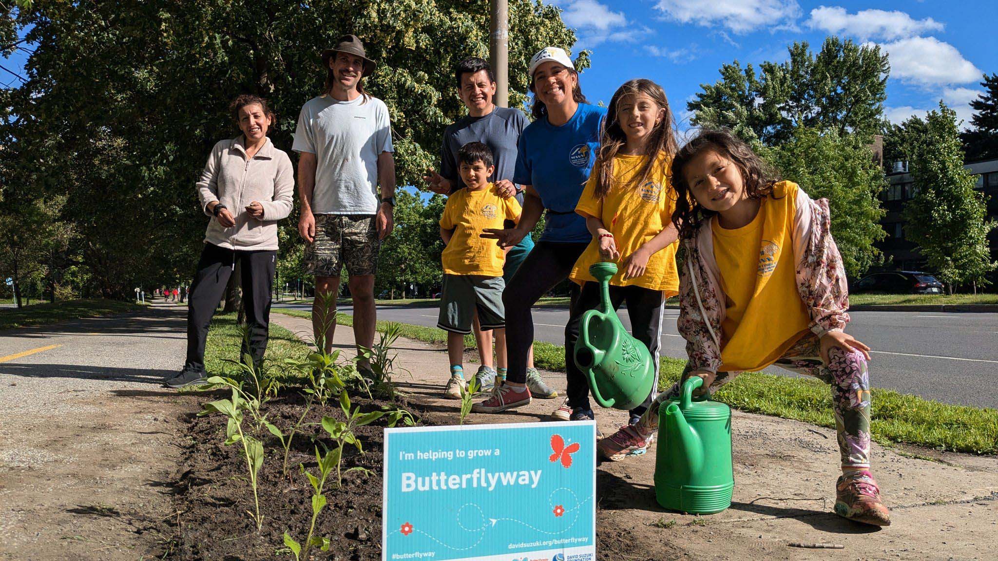 A group of people posing with watering cans and a newly planted street garden