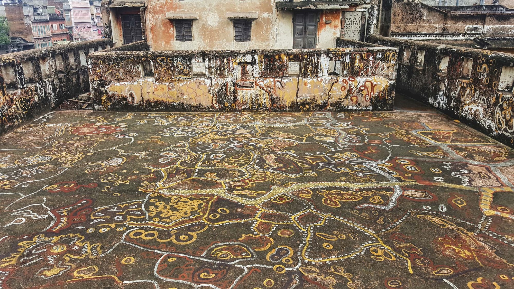 An urban courtyard painted with abstract designs in earthy reds, yellows and white