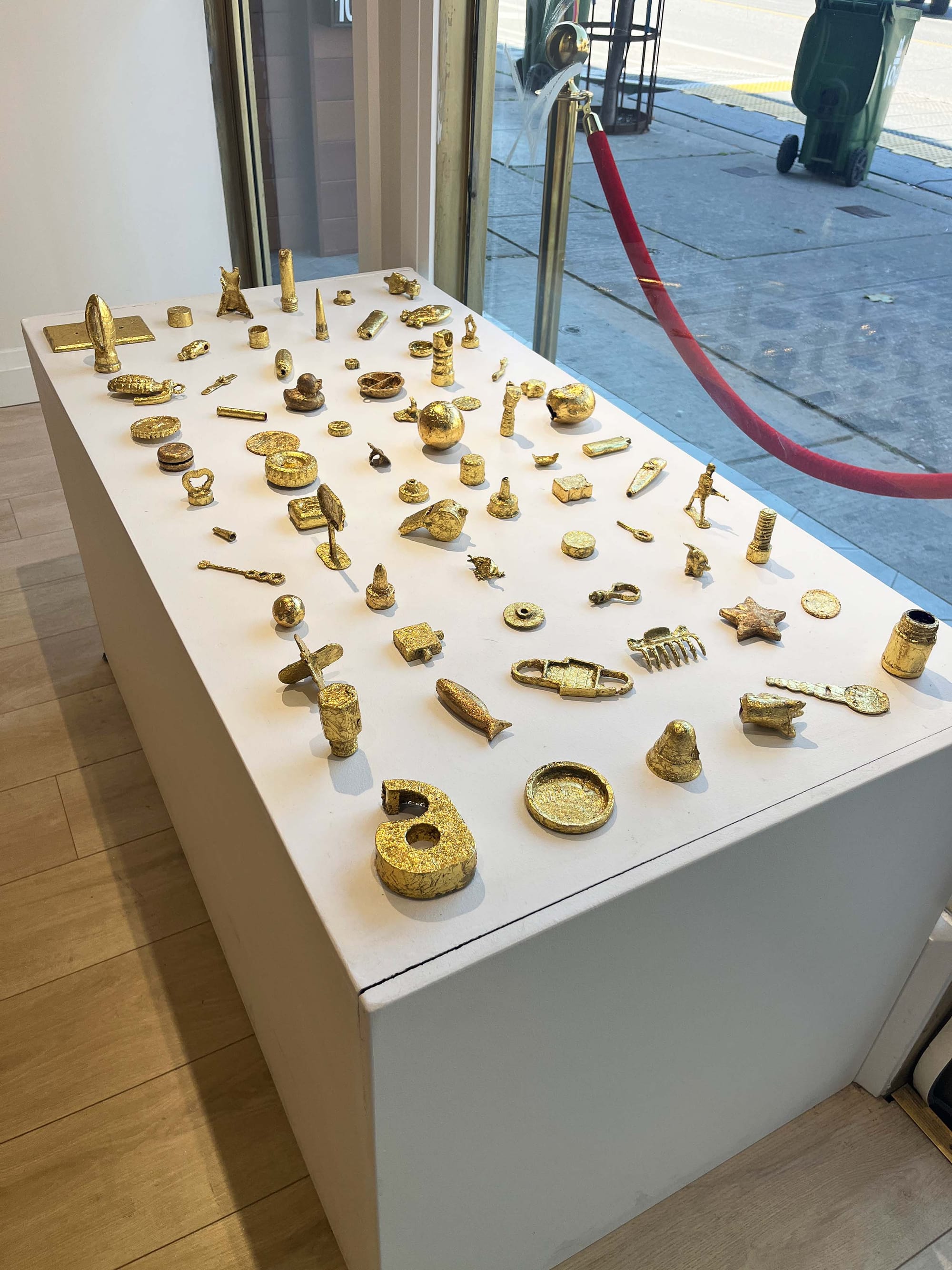 A white table covered with various gold items including a tape dispenser, tray, whistle and bolt.