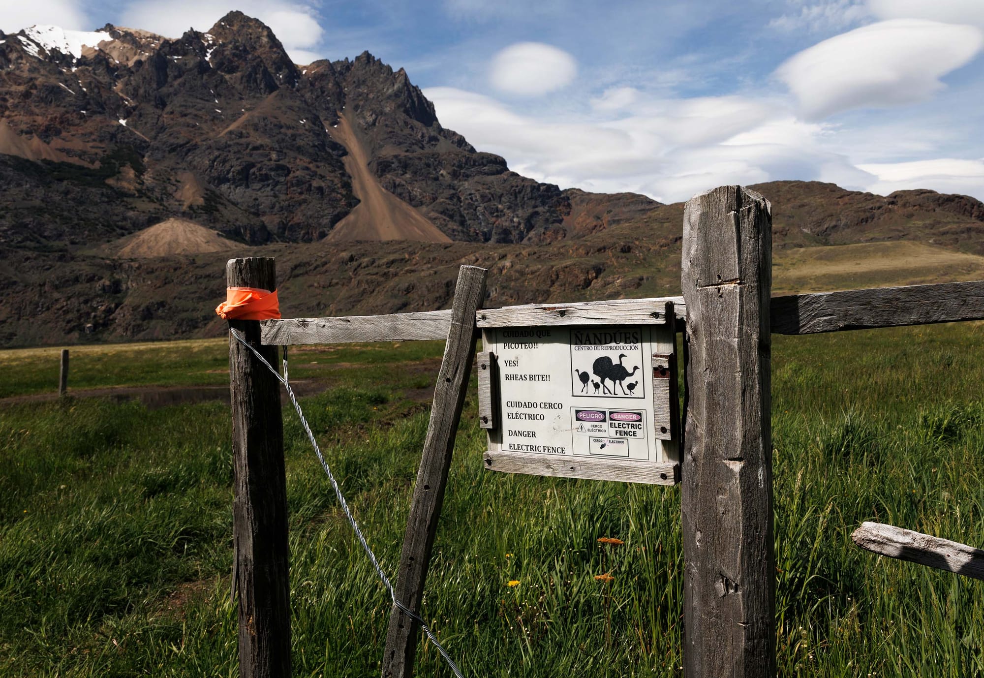 A warning sign on a wooden fence in a mountainous outdoor landscape
