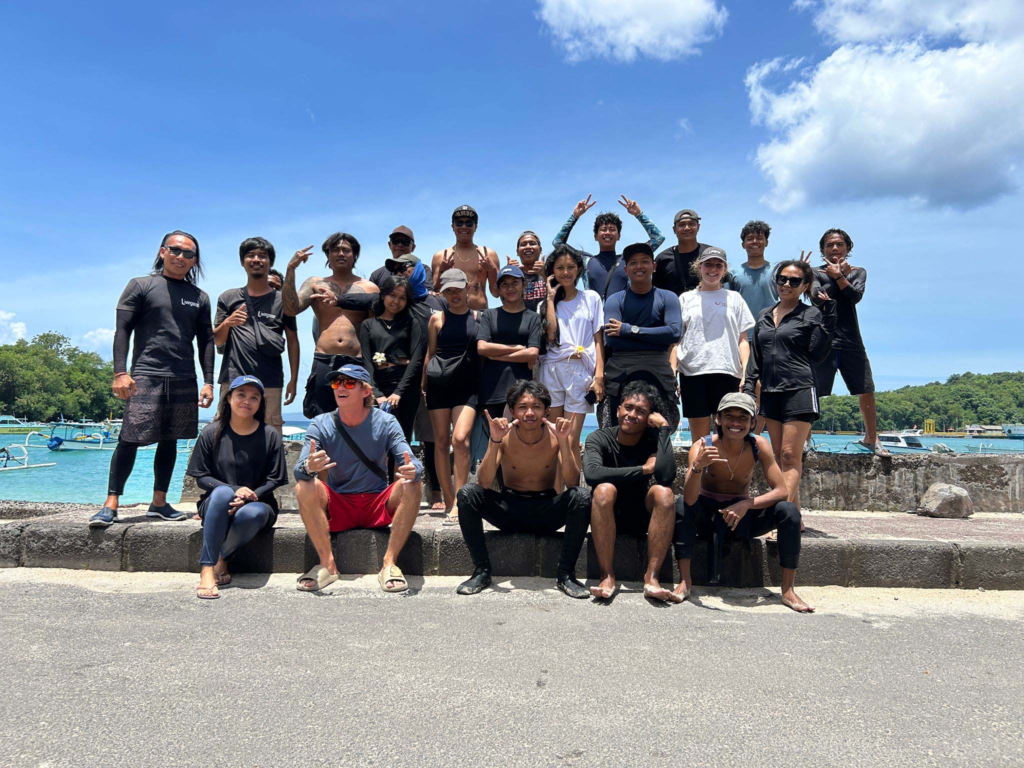 A group of people posing for the camera in front of an ocean on a sunny day