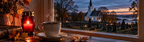 En kaffekopp og et tent gravlys i vinduet en oktoberkveld, med en hvit kirke og kirkegården utenfor