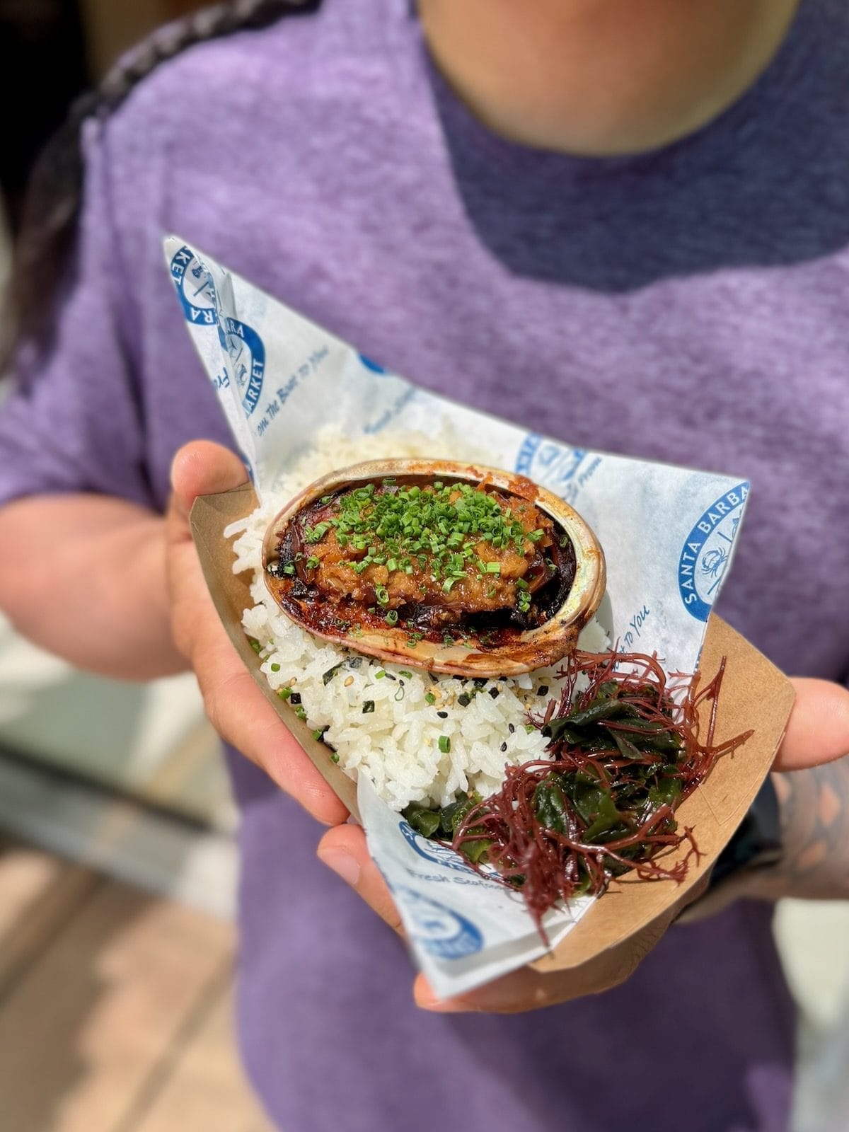Braised California red abalone in shell served over rice with seaweed salad at Santa Barbara Fish Market