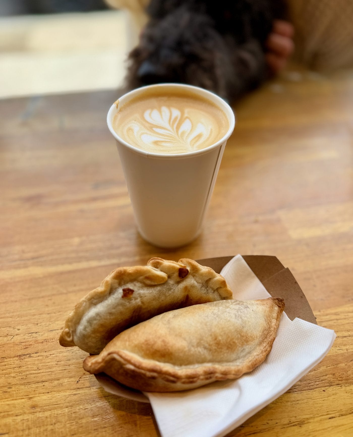 Flat white latte art next to Buena Onda empanadas at Dart Coffee in Santa Barbara