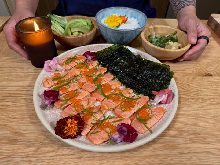 Seared steelhead with garnishes and seaweed and rice on the side with avocado and cucumber