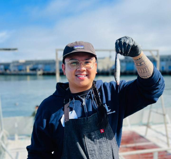 Chef Geronimo Ramos holding a fresh anchovy on the San Francisco waterfront.
