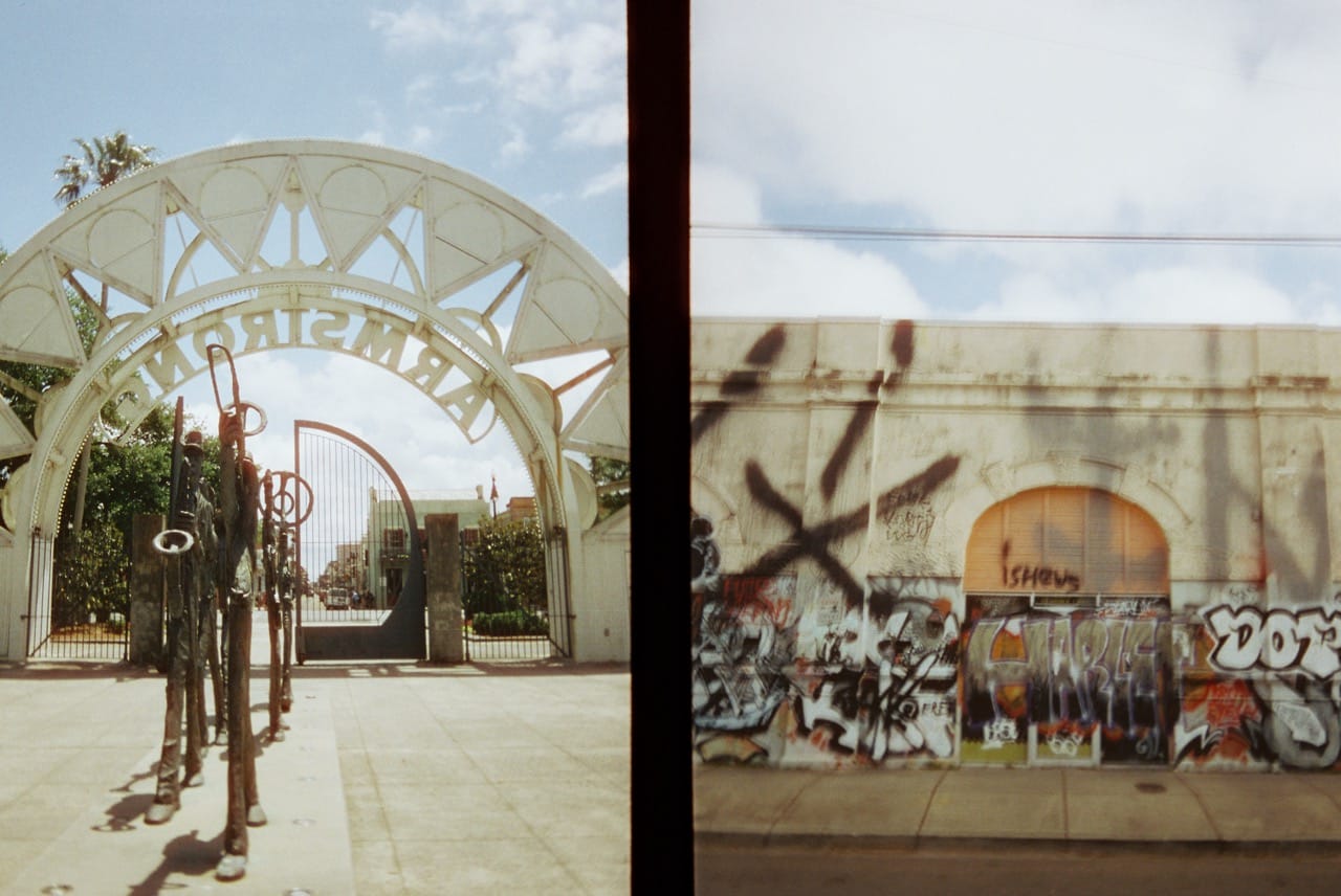A two-part color photograph, one side the gate into Louis Armstrong Park in New Orleans, the other side a graffitied wall with a closed gate