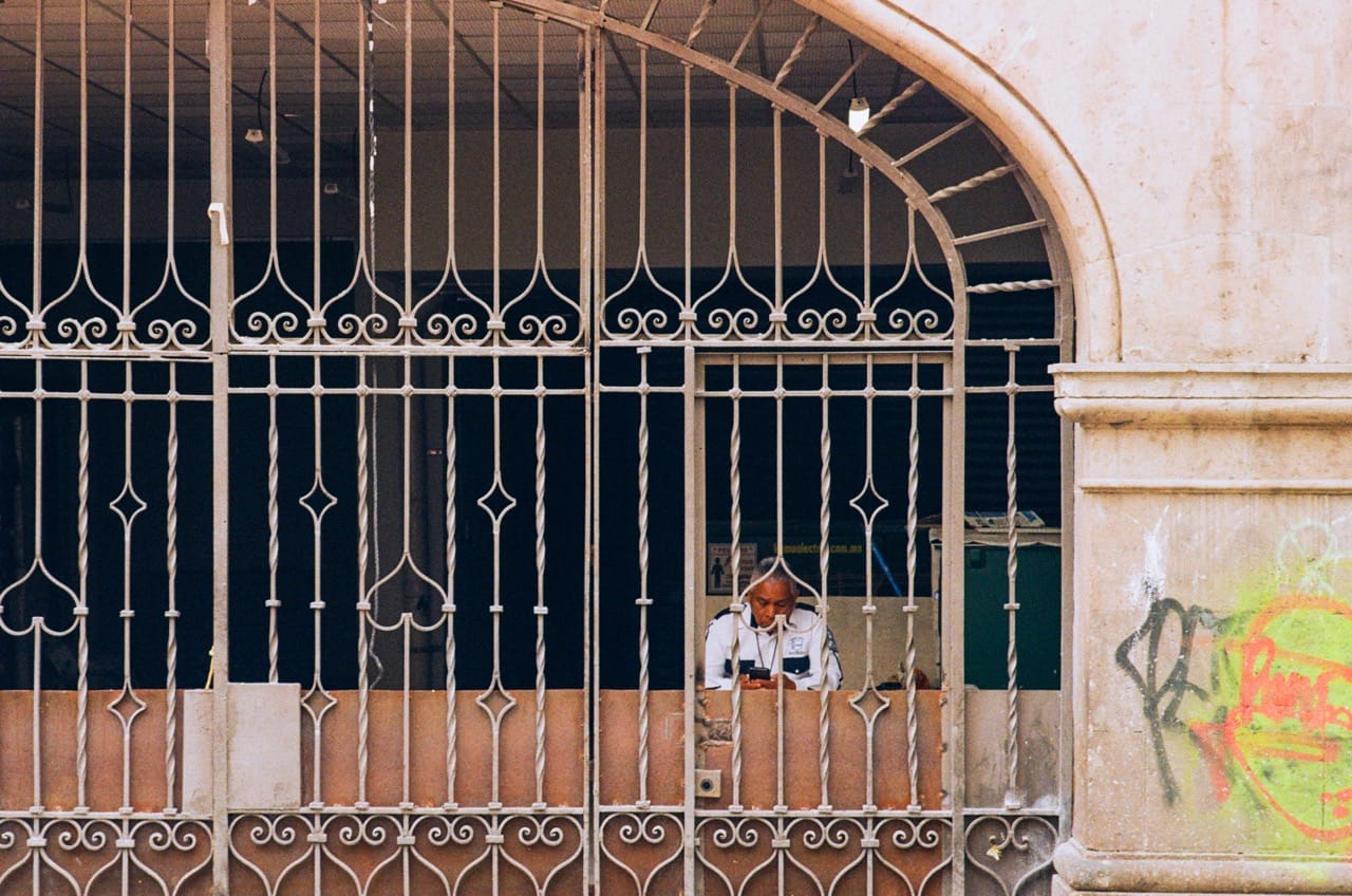 a color photo of a security officer behind an elaborate iron gate