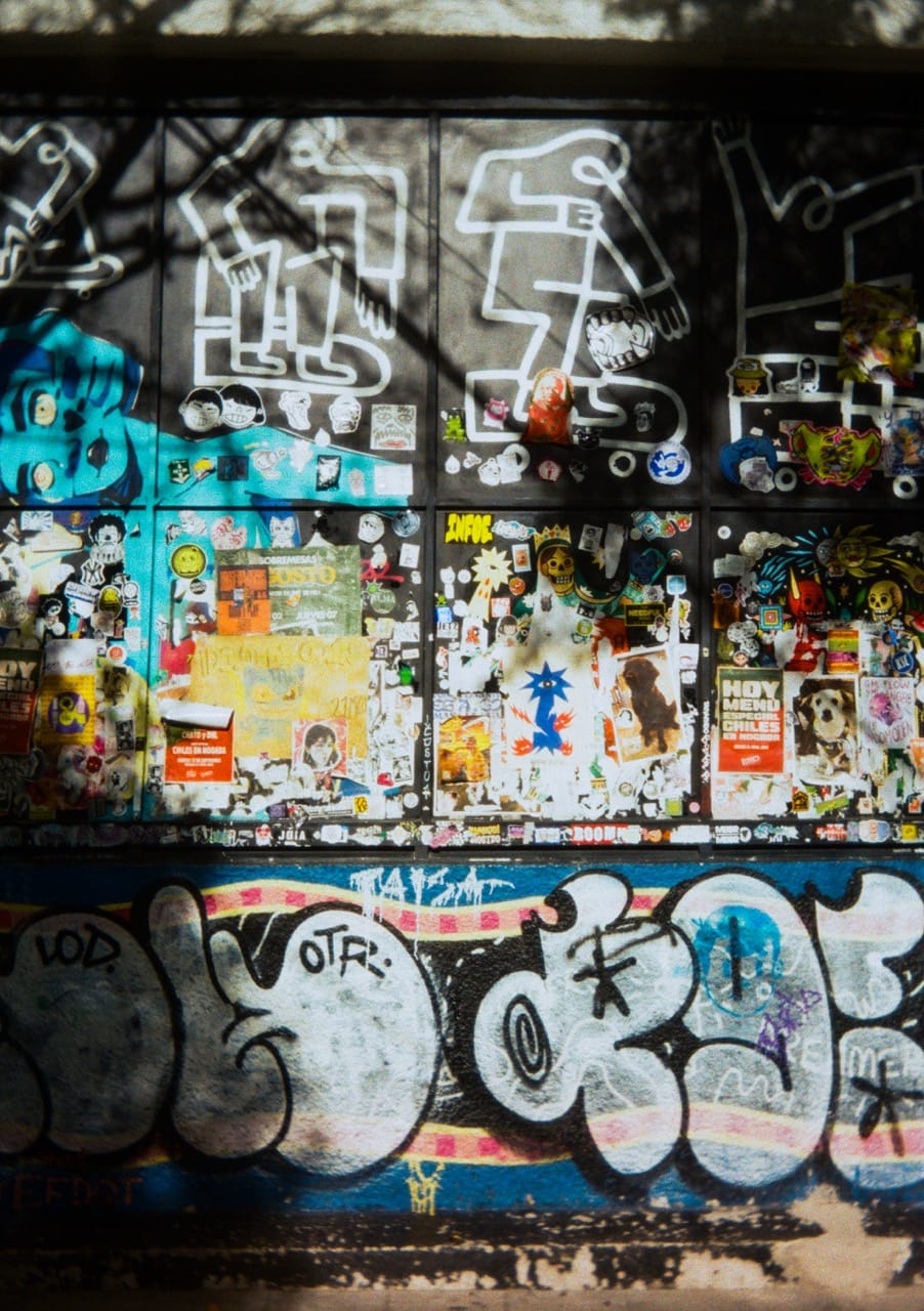 a photograph of the side of a building, covered in graffiti, stickers, and posters of all colors