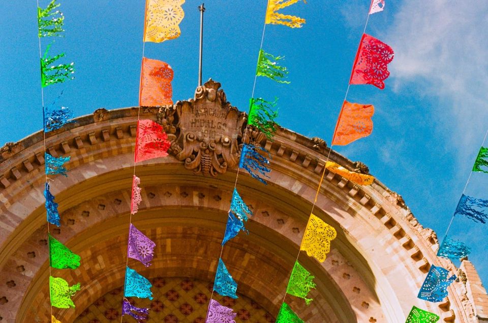 a color photograph of the stone arch above Mercado Hidalgo, with strings of colored flags crossing the foreground