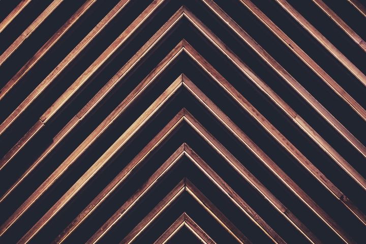 Upward-pointing wooden chevron beams on a dark ceiling, representing strategic direction in building an enterprise AI business case.