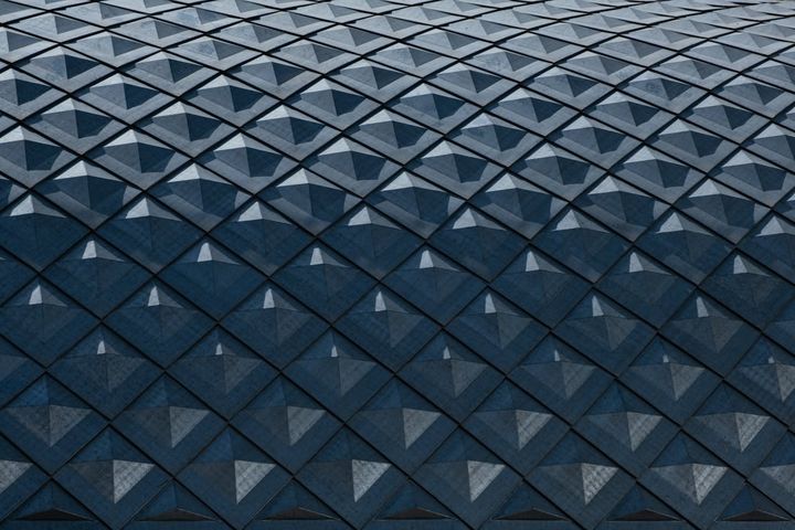 Abstract geometric pattern of teal and blue diamond shapes on a modern building facade