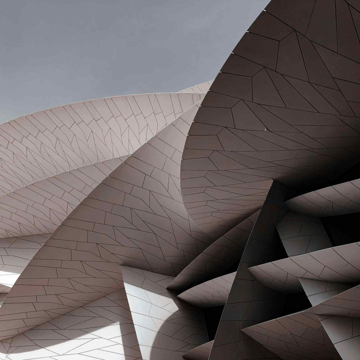 Flowing curved architectural surfaces with irregular stone-like tile pattern and dramatic light and shadow