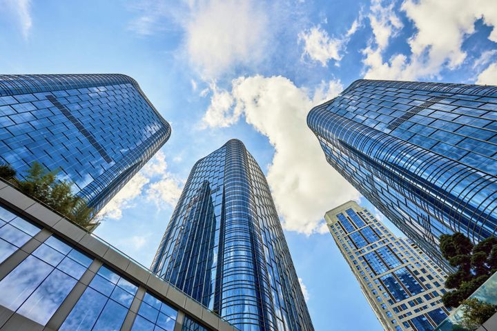 Glass skyscrapers viewed from ground level against a blue sky, representing enterprise-scale technology architecture decisions