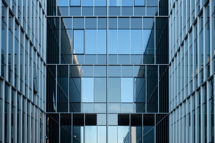 Symmetrical glass and steel corporate office building facade reflecting sky, representing enterprise-scale technology infrastructure