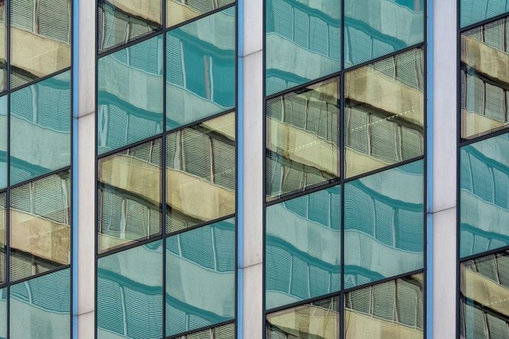 Modern glass office building exterior with geometric reflections — enterprise corporate architecture