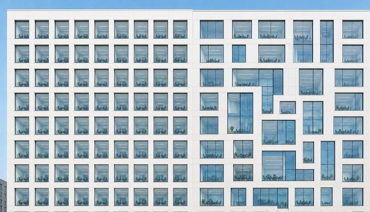 Geometric office facade with light patterns shifting from uniform grid to irregular distribution, illustrating the fixed to variable shift in enterprise AI cost models