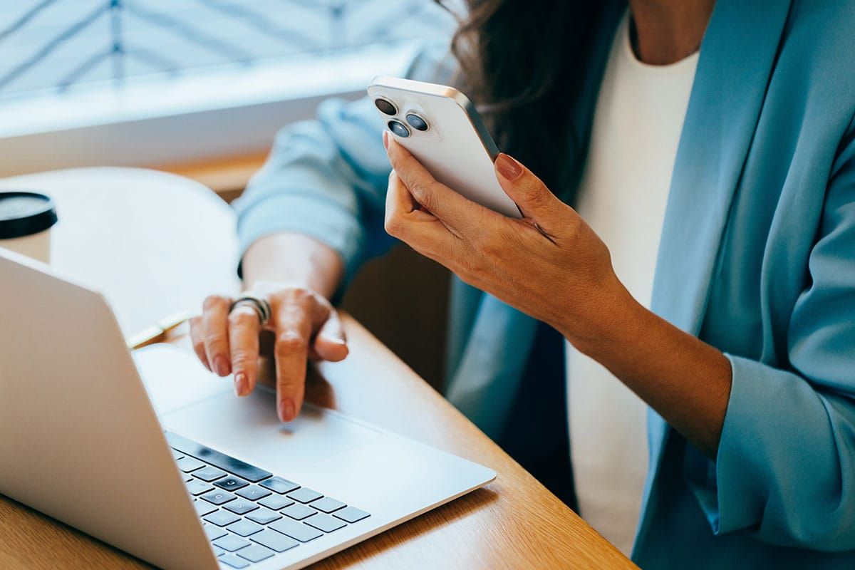 Professional woman using a computer while on a phone call, representing human judgment and clarity in an AI-driven workplace.
