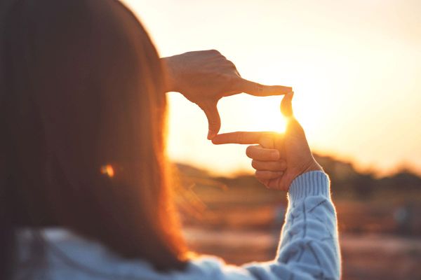A woman sees the sun cropping the image with her fingers.