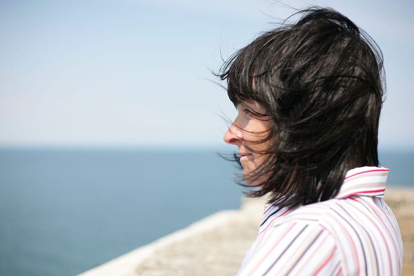A middle-aged woman looking out over a body of water, reflecting on her life with perspective.