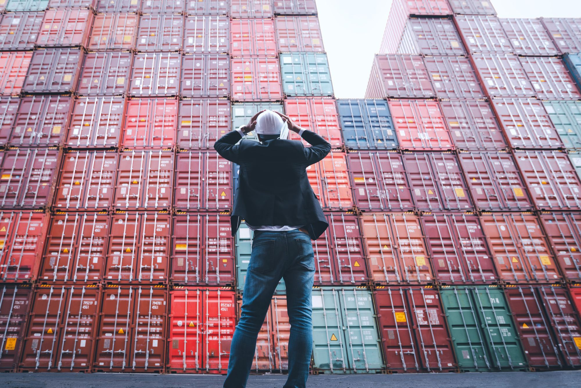 Gerente de inventario frustrado observando contenedores apilados por exceso de stock