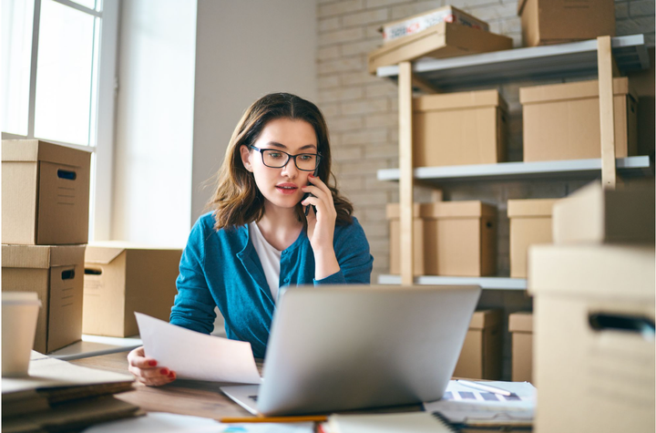 Mujer llamando a un vendedor mientras revisa una factura en su computadora portátil