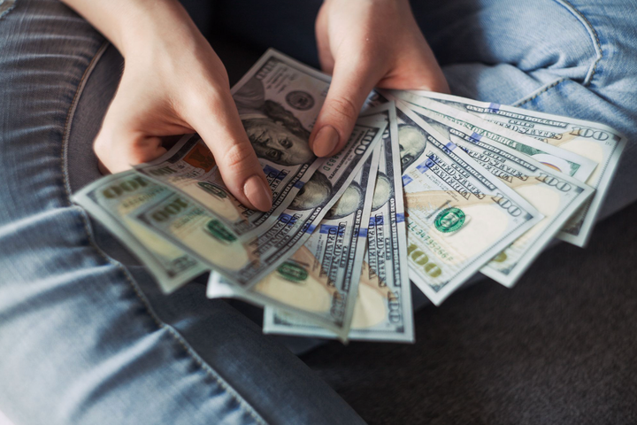 Chica sosteniendo billetes de dólar estadounidense.