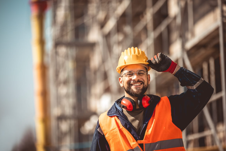Gerente de obra en un sitio de construcción, llevando chaleco de seguridad y casco.