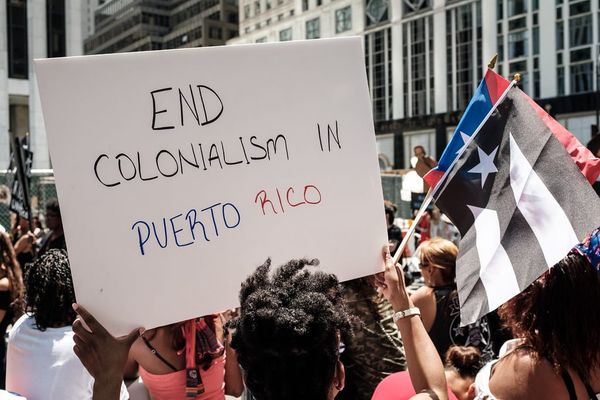 Demonstrators hold Puerto Rico flags and a sign reading "End colonialism in Puerto Rico"