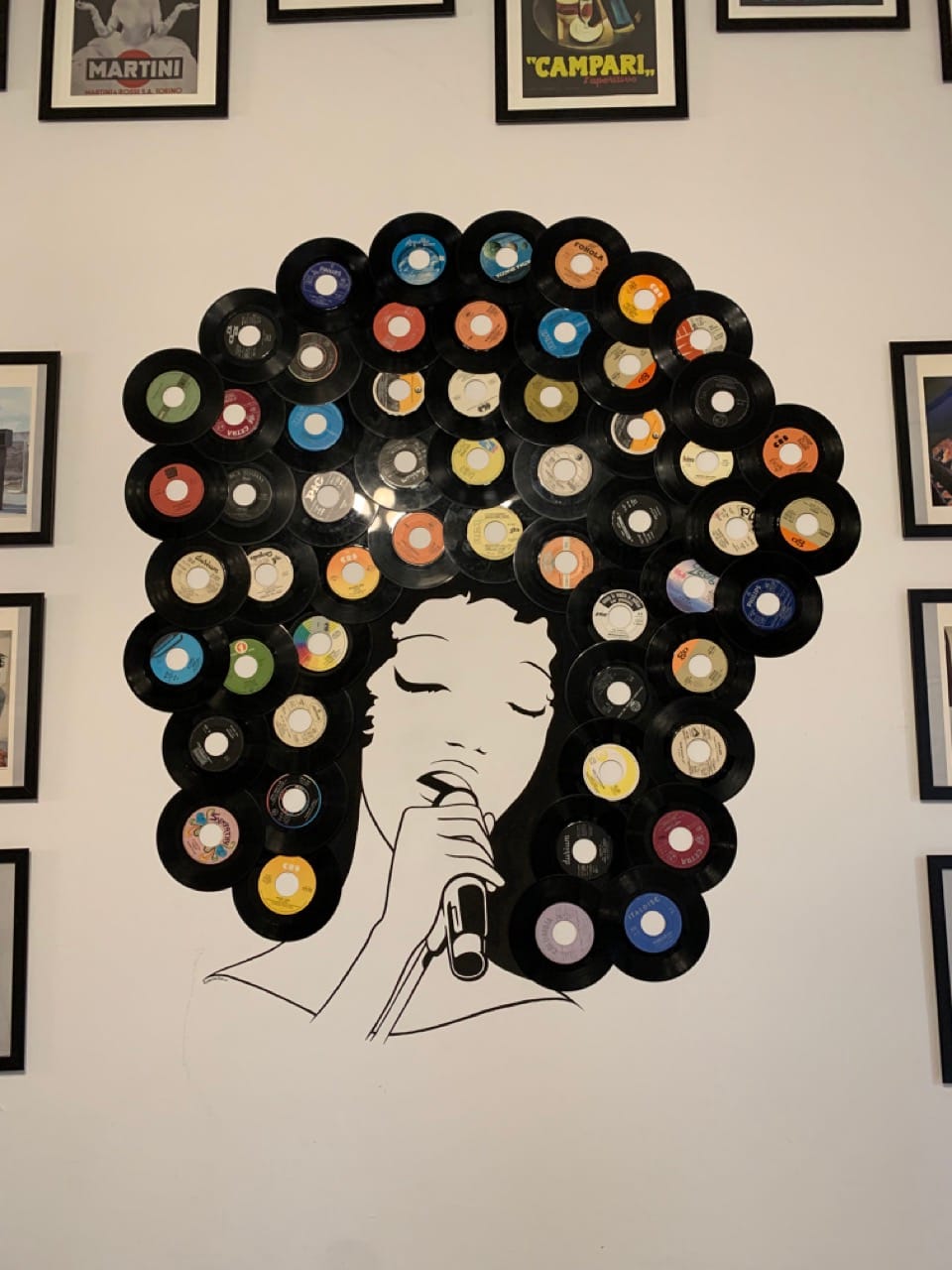 A mural of a woman singing. Her hair is made of vinyl records.