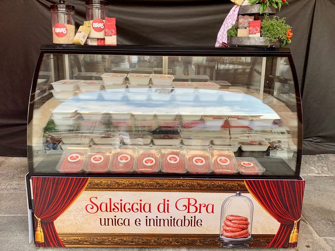 A refridgerated food stand containing packets of Bra sausage.