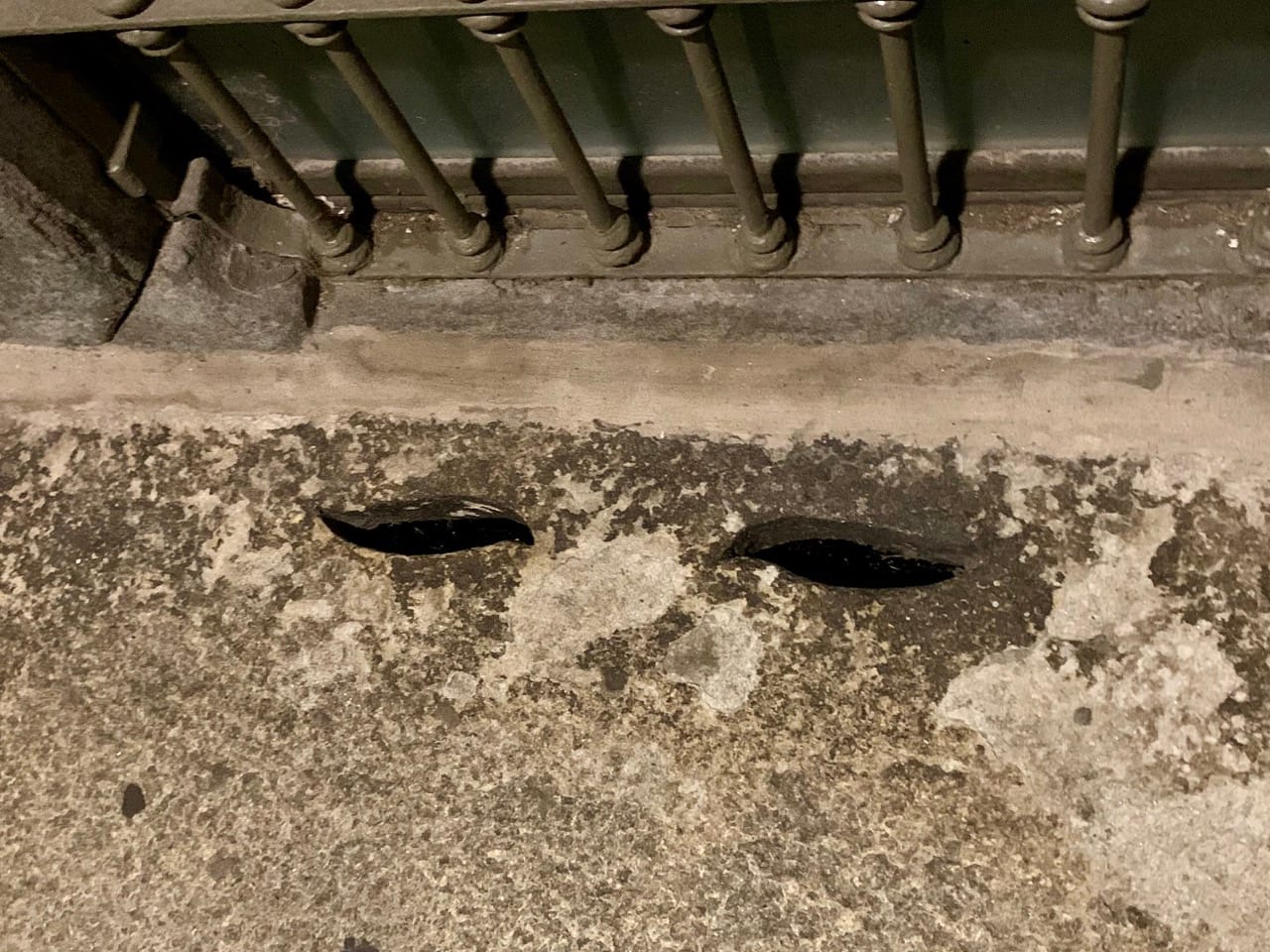 Two eye-shaped holes carved into a pavement.