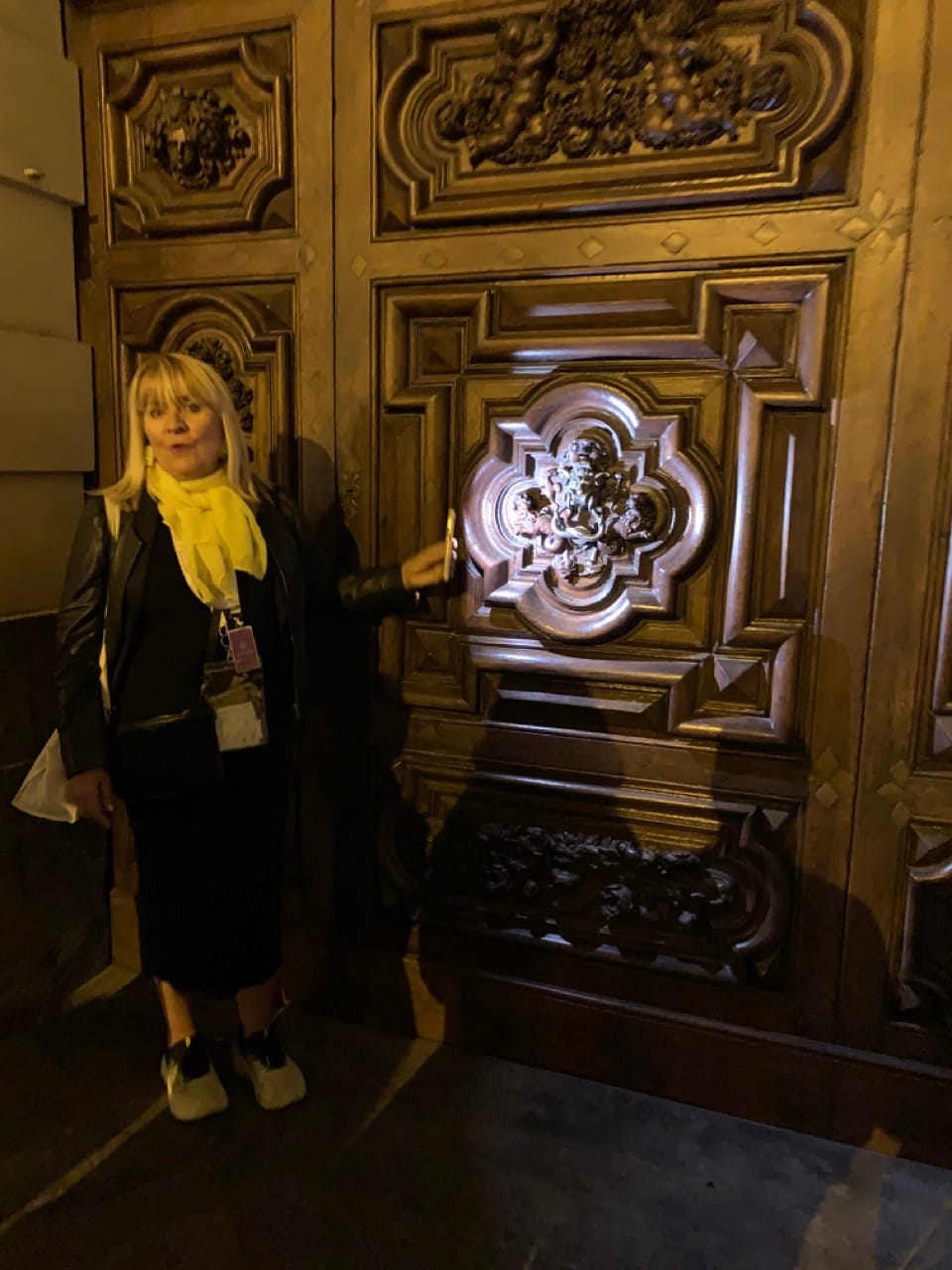 A woman shines a light on a wooden door decorated with an image of the devil.