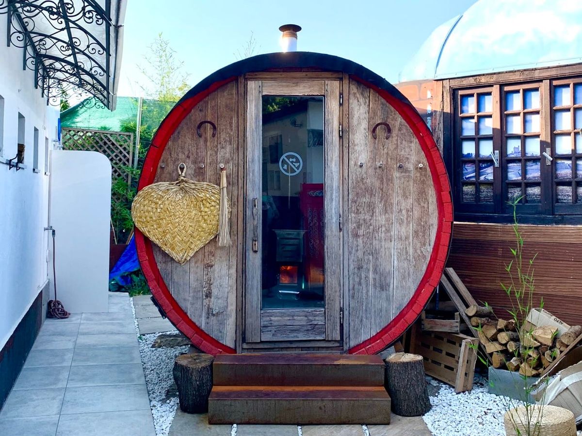 A converted Barolo barrel with a glass door and a wood stove burning inside.