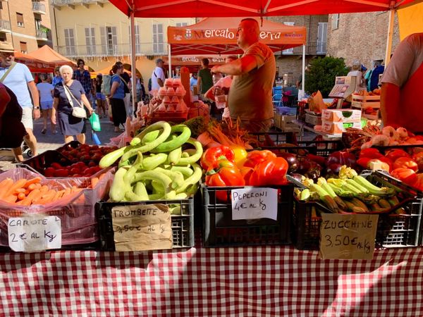 A market stall displaying carrots, courgettes, peppers, and tomatoes