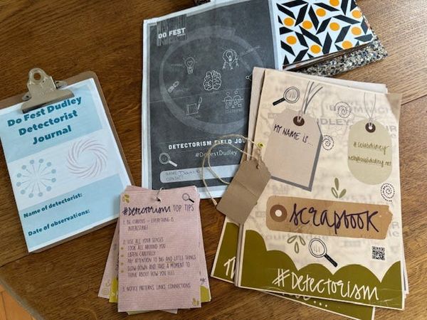 photo on wooden table of four different detectorism tools including a journal, a lanyard, a scrapbook