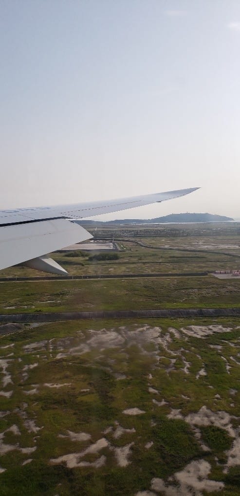A view out of the window of a plane coming in for a landing. Includes the wing of the airplane.